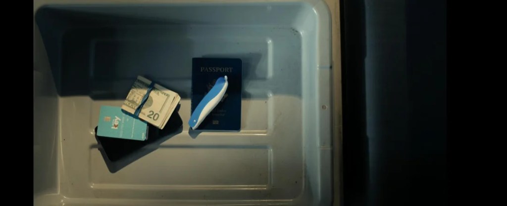 A close-up view of a light-colored container displaying a passport, a stack of cash, and two bank cards.